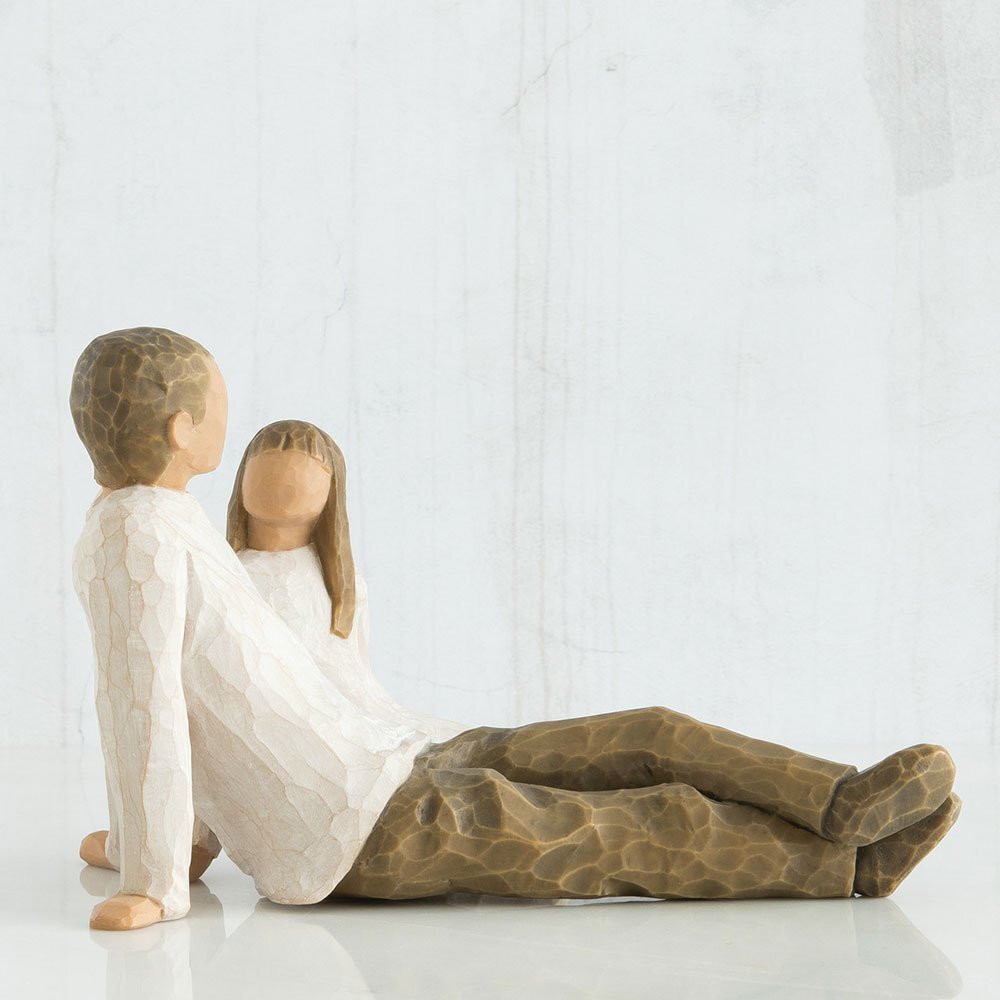 Father and Daughter Figurine by Willow Tree. Side View - Figure of seated male in cream shirt and dark pants, with young girl in cream dress seated by his side