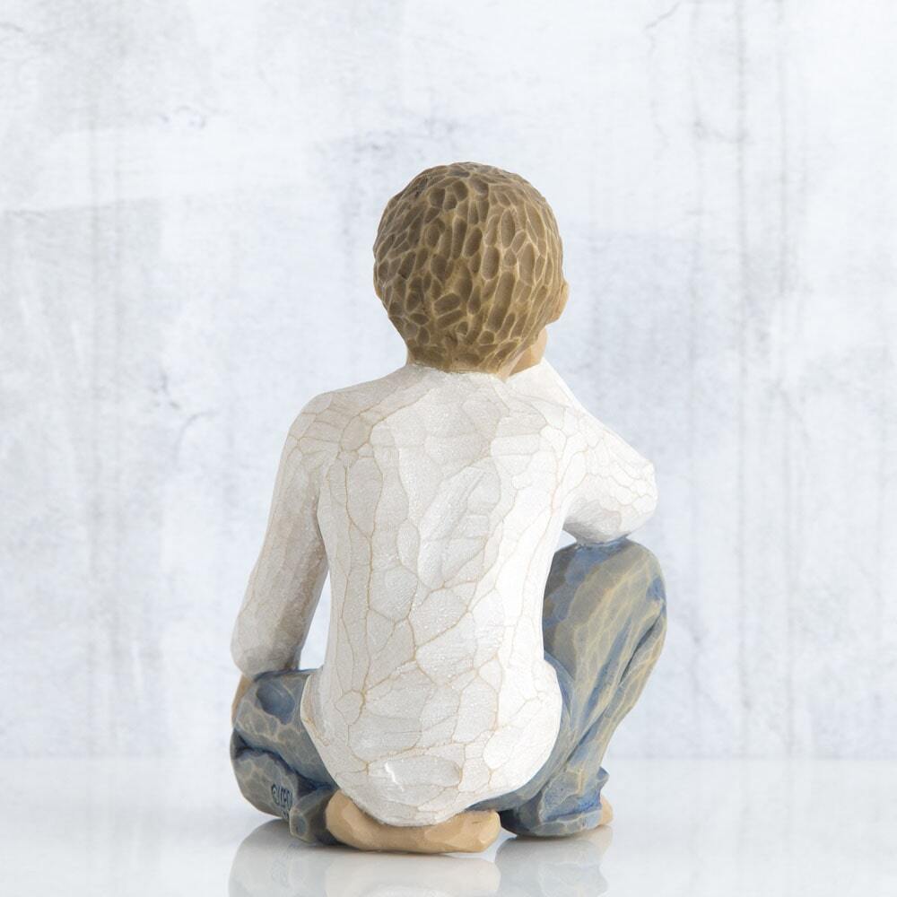 Figure of half-kneeling boy in cream shirt and blue jeans, with hand under chin