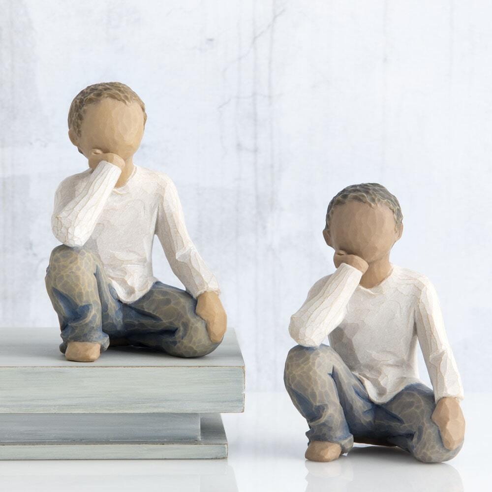 Showing both light and dark versions of this figurine. Figure of half-kneeling boy in cream shirt and blue jeans, with hand under chin