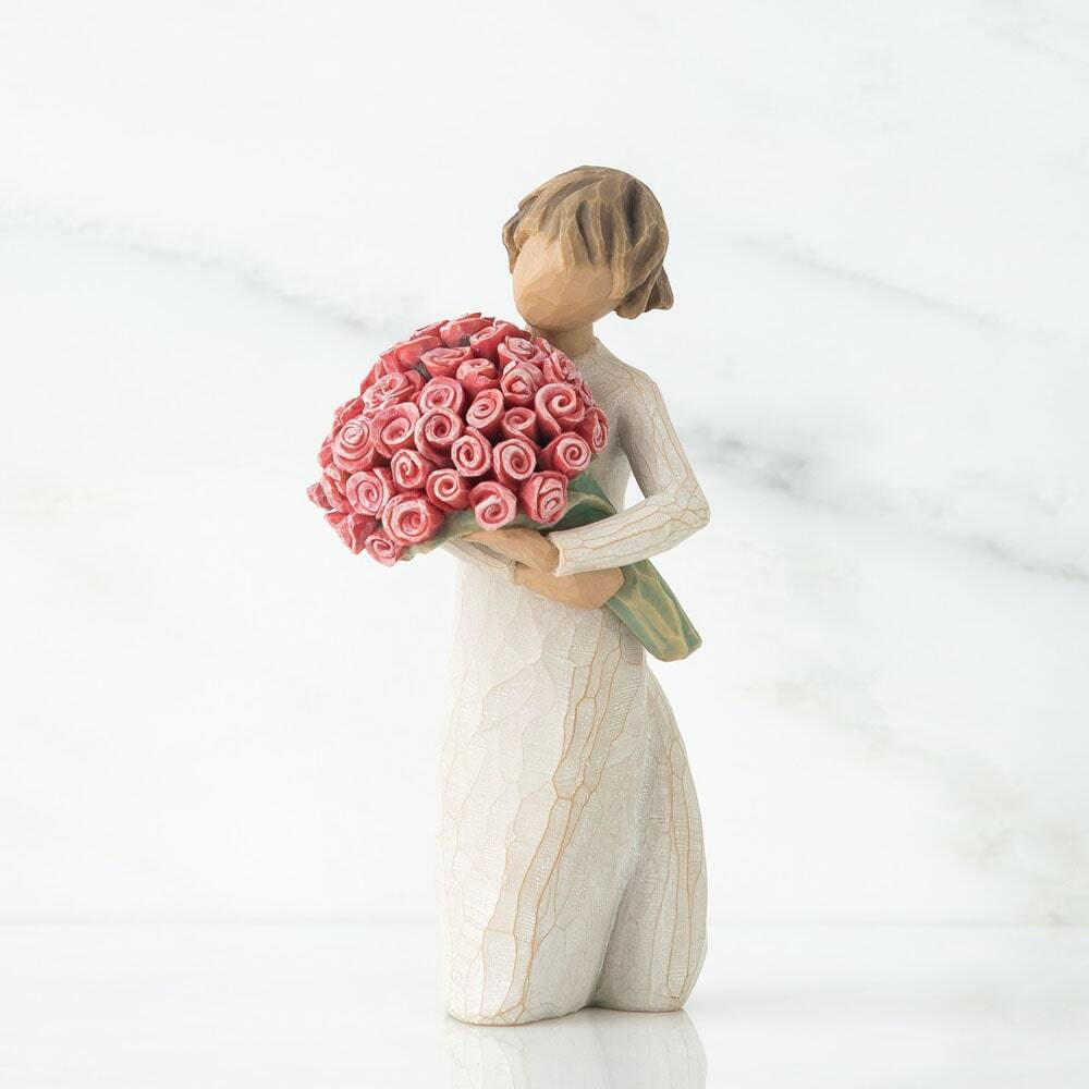 Standing female figure in cream dress holding large bouquet of pink roses