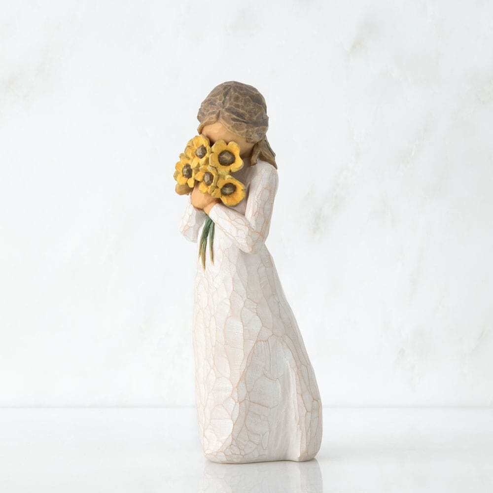 Standing figure in cream dress, holding large bouquet of yellow sunflowers up to face