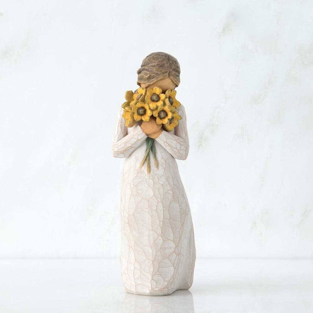 Standing figure in cream dress, holding large bouquet of yellow sunflowers up to face