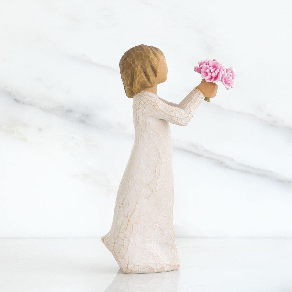 Standing figure in cream dress, holding out small bouquet of pink peonies