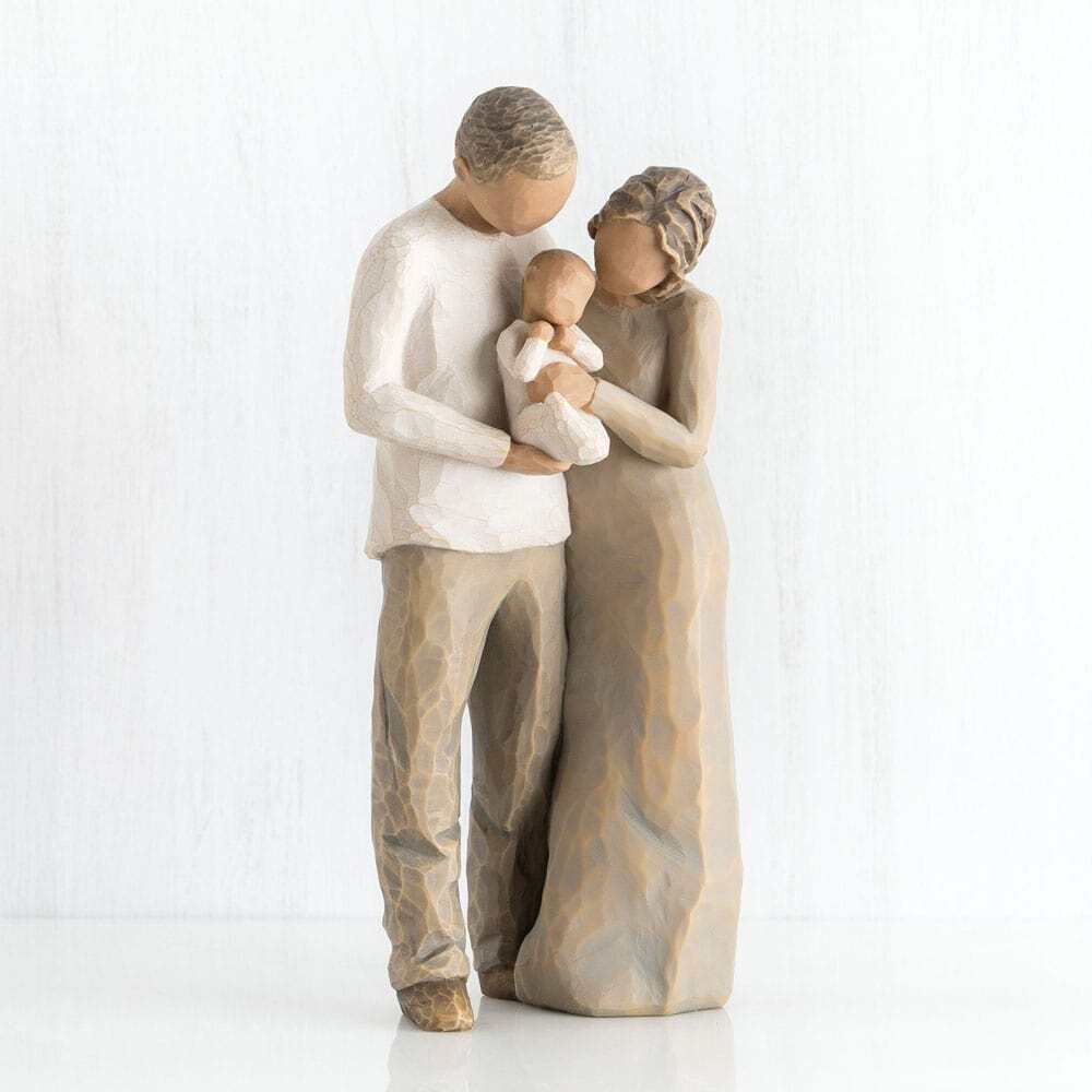 Figure of couple with darker skin tone and hair colour, standing next to each other, holding a baby between them