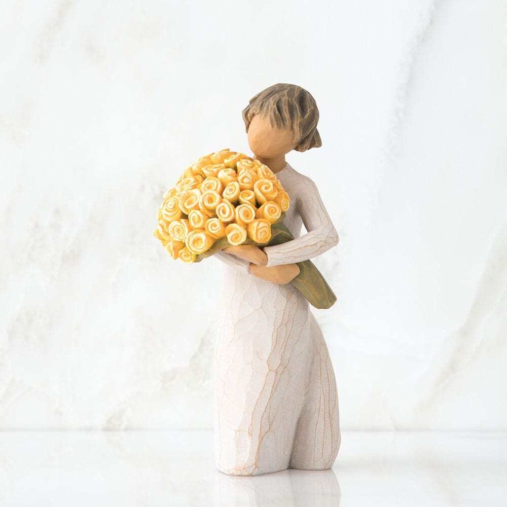 Standing figure in cream dress, holding large bouquet of yellow roses in her arms