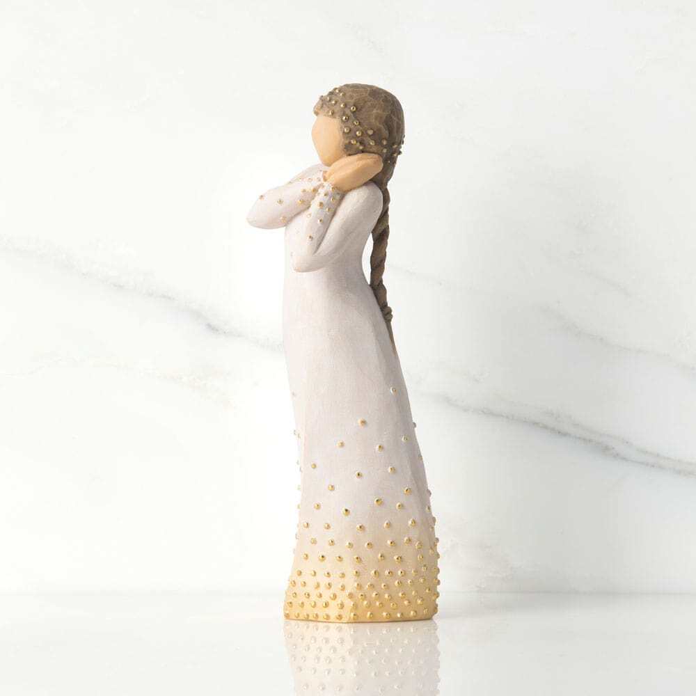 Standing figure in cream dress, holding up arms to face in wistful gesture. Bottom of dress embellished with gold and gold-leaf dots